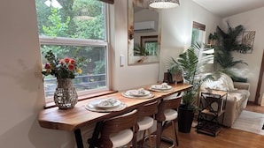A dining area with a wooden table set for four, surrounded by chairs. - Luxury Cabin, fire pit, BBQ, WiFi, forest view, river access (Richland)