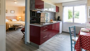 Una camera d'albergo compatta con angolo cottura, zona pranzo e un letto.