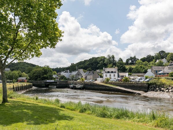 A riverside town with a stone bridge, grassy banks, and buildings in the background. - La Littorine by Interhome (Penzé-Taulé)