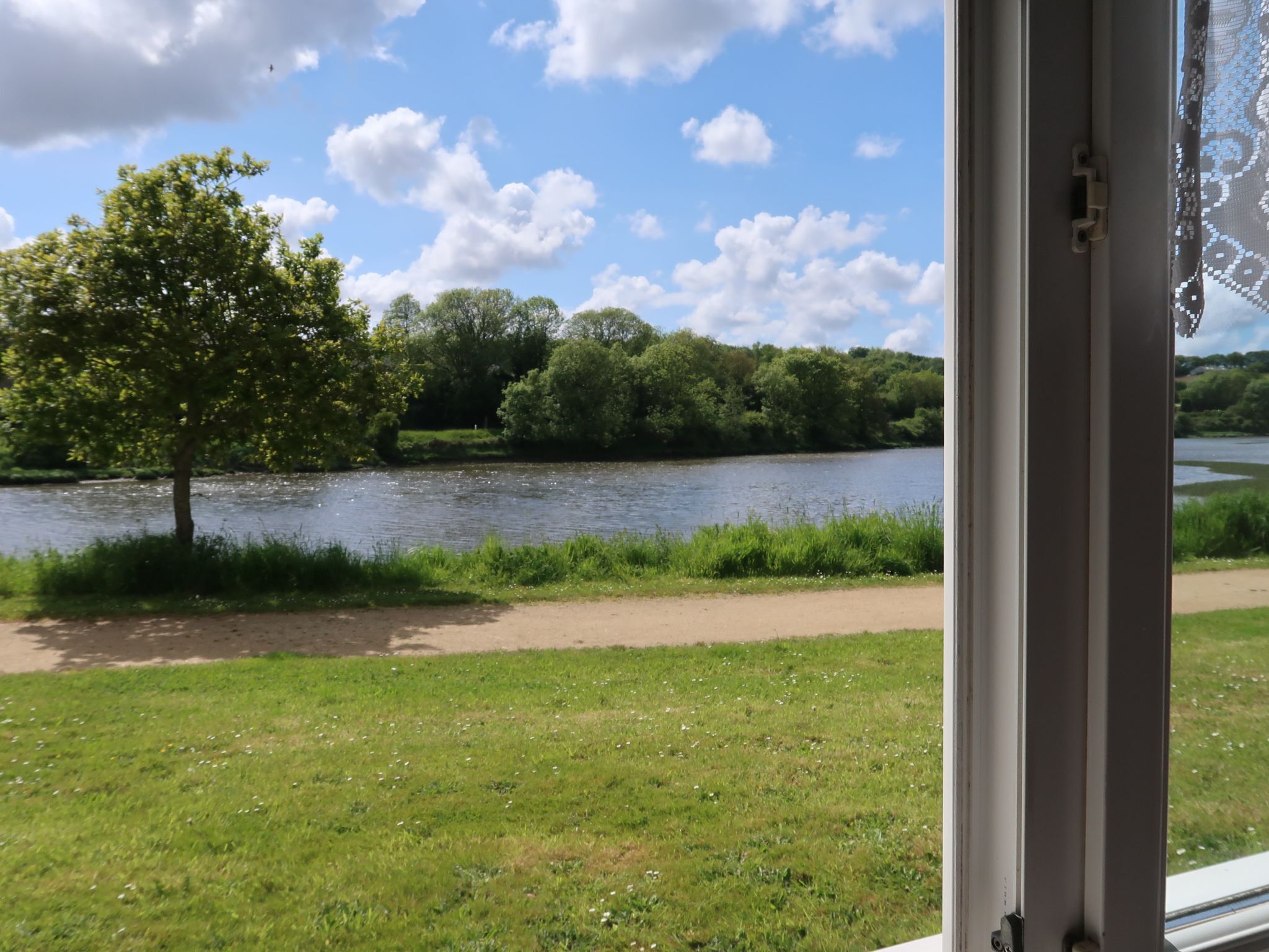 A river view from a window with a path and greenery.