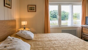 Una camera da letto con un letto, un comodino con una lampada, una cassettiera e una finestra con tende.