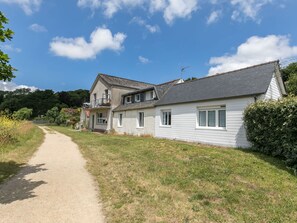 Une maison à deux étages avec un chemin de gravier menant à l’entrée.