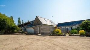 A rustic barn-style building with a dirt driveway and a fenced yard. - Les Azalées by Interhome (Ploumilliau)