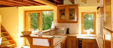 Una cocina con armarios de madera, un ventanal grande y una estufa integrada.