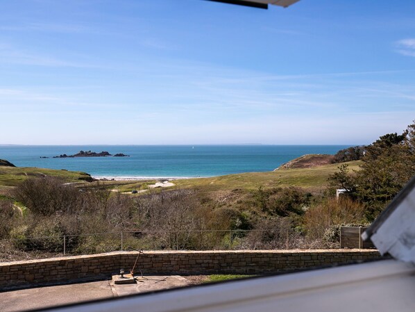 A coastal view with a stone wall, grassy area, and a clear blue sky.
