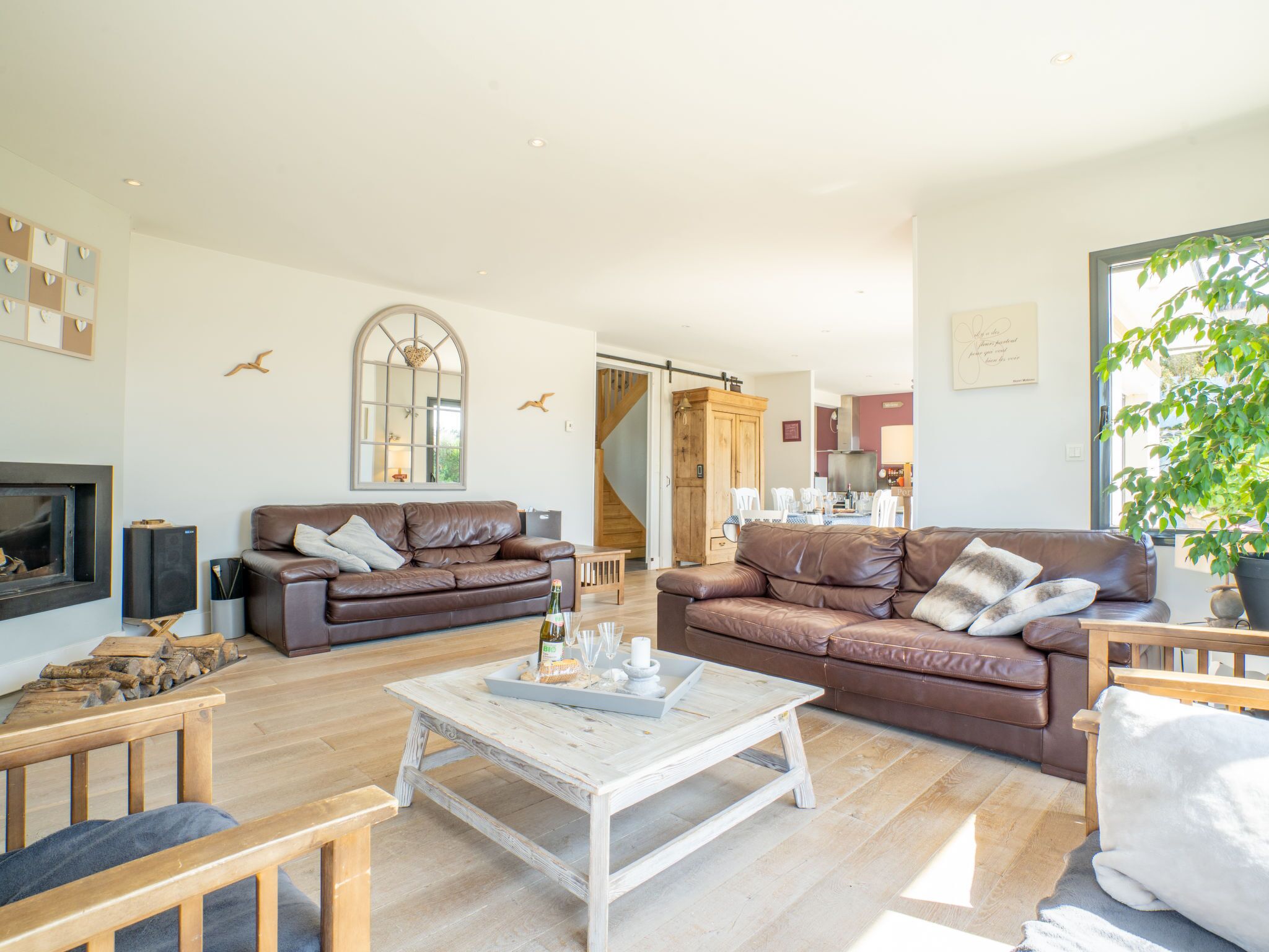 A spacious living room with two brown leather sofas, a white coffee table, and a wooden TV stand.