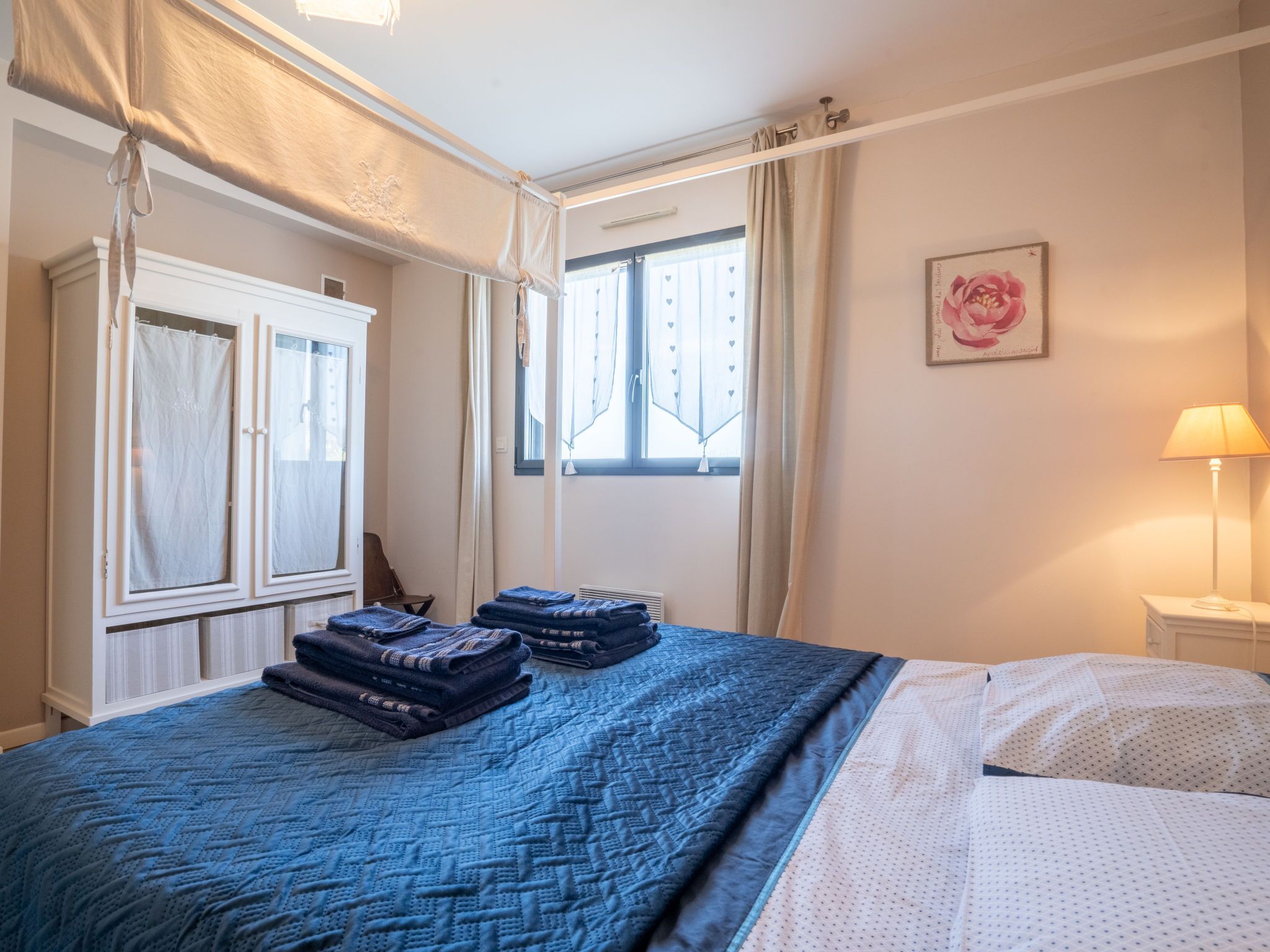 A bedroom with a large bed, a wardrobe, a window with curtains, and a bedside lamp.