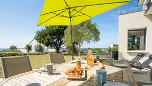 An outdoor dining area with a wooden table, chairs, a yellow umbrella, and a view of the sea. - Vacation home Hidel by Interhome (Plouarzel)