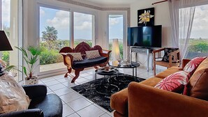 A spacious living room with a large TV, comfortable seating, and a view of the outdoors.