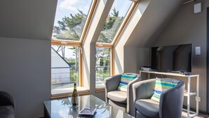 Une chambre de style loft moderne, dotée de fenêtres de toit, d’une table en verre, d’un canapé et d’un téléviseur.