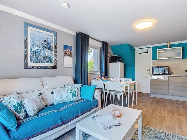 A compact living space with a sofa, dining table, and kitchenette.