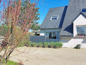 A house with a grey roof, a small window, and a gravel driveway.