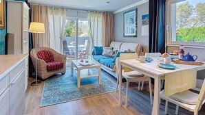 A cozy living area with a sofa, a dining table, and a view through a glass door. - Ty-Rozen by Interhome (Locquirec)