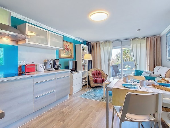 A modern kitchen with a dining area, a wicker chair, and a view of the outdoors.