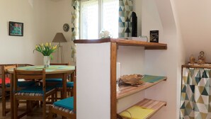 Un coin repas accueillant avec une table ronde en bois, des chaises rembourrées bleues et un vase de tulipes jaunes.