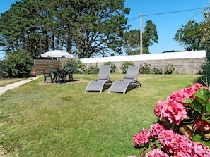 Enjoy outdoor dining or relaxation on the deck, surrounded by lush trees and a lawn.