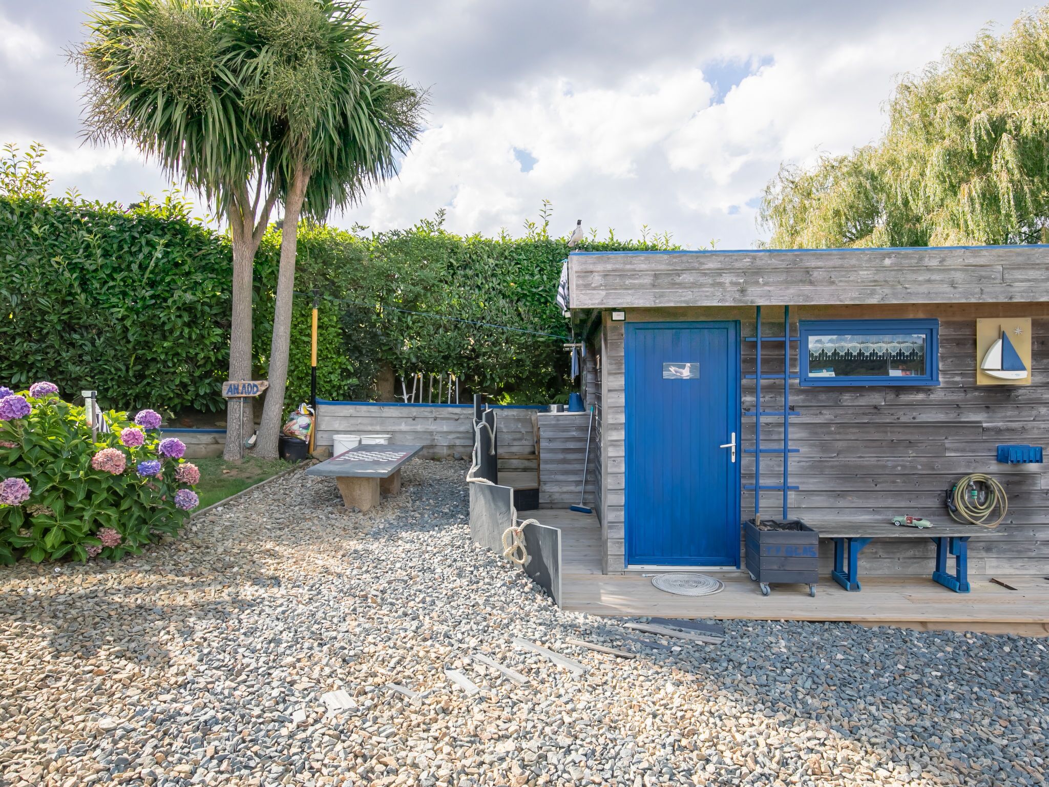 A small wooden building with a blue door, a bench, and a table outside.