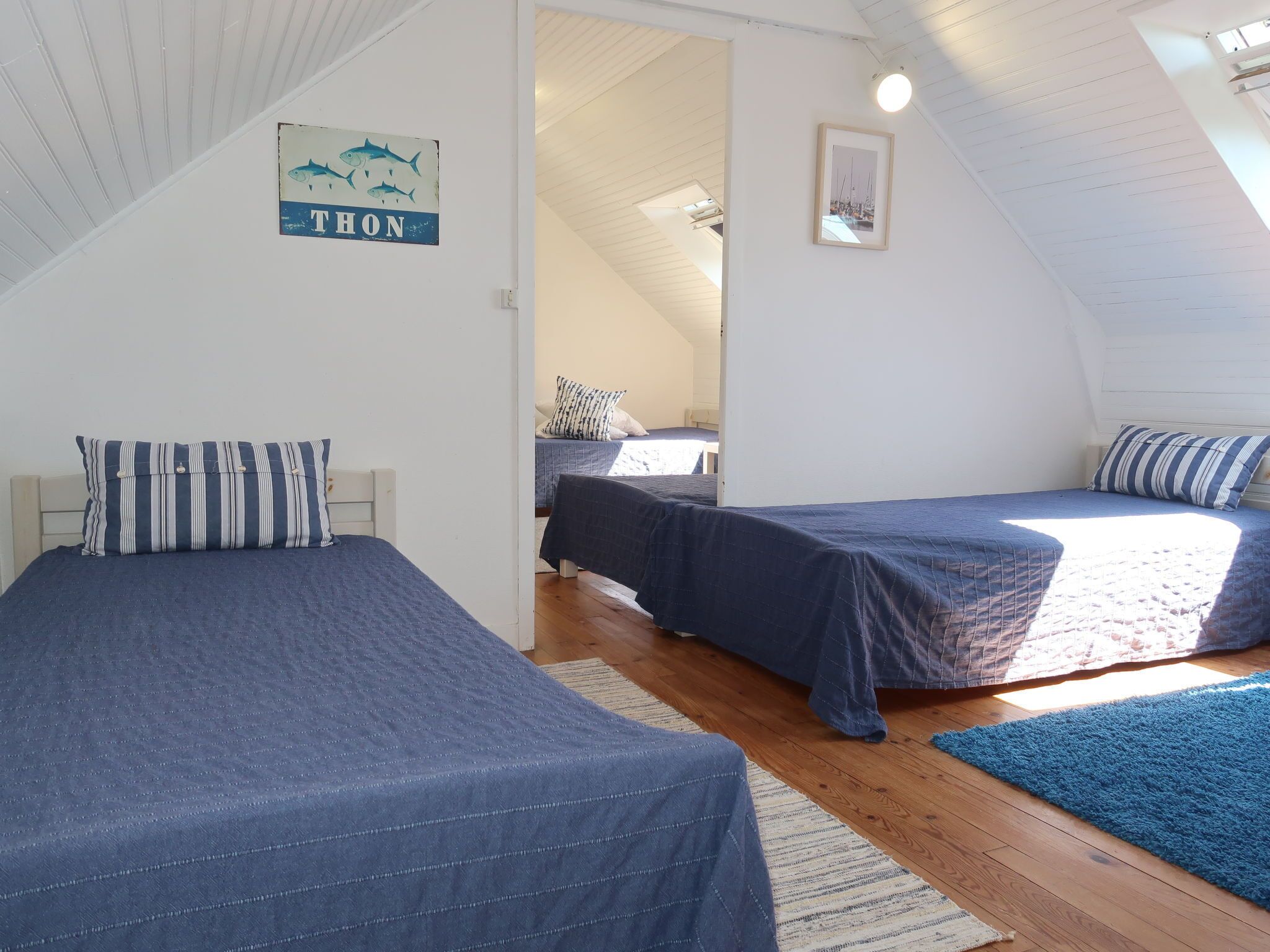 A cozy attic bedroom with two beds, wooden floors, and a sloped ceiling.