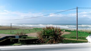 Blick auf den Ozean von einem Balkon, im Vordergrund eine Rasenfläche mit Picknicktischen.