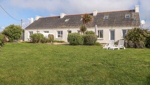 A two-story house with a tiled roof, white exterior walls, and a well-maintained lawn.