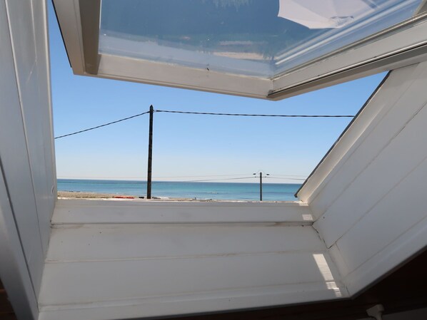 A skylight with a view of the beach and ocean.