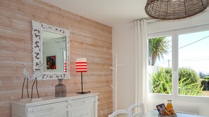 A dining area with a white table, chairs, a decorative mirror, and a lamp.