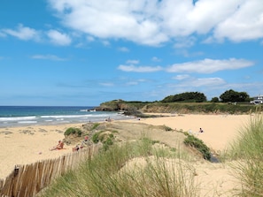 A beach with a wooden fence, sandy dunes, and a building on a cliff. - Tal ar Mor by Interhome (Le Pouldu)