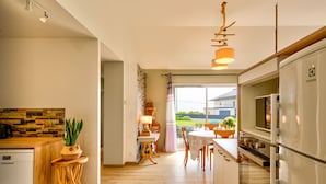 A modern kitchen with a wooden countertop, a built-in oven, and a dining area with a table and chairs. - Vacation home Orphée by Interhome (Telgruc sur Mer)