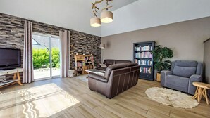 A modern living room with a large flat-screen TV, leather sofa, and a bookshelf. - Vacation home Orphée by Interhome (Telgruc sur Mer)