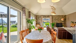 A dining area with a table set for four, surrounded by wooden chairs. A large window provides a view of the outdoors. - Vacation home Orphée by Interhome (Telgruc sur Mer)