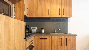 Une cuisine moderne avec des meubles en bois, des appareils électroménagers en acier inoxydable et un four encastré.