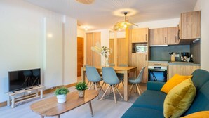 Un salon moderne avec un téléviseur, une table à manger et un canapé.