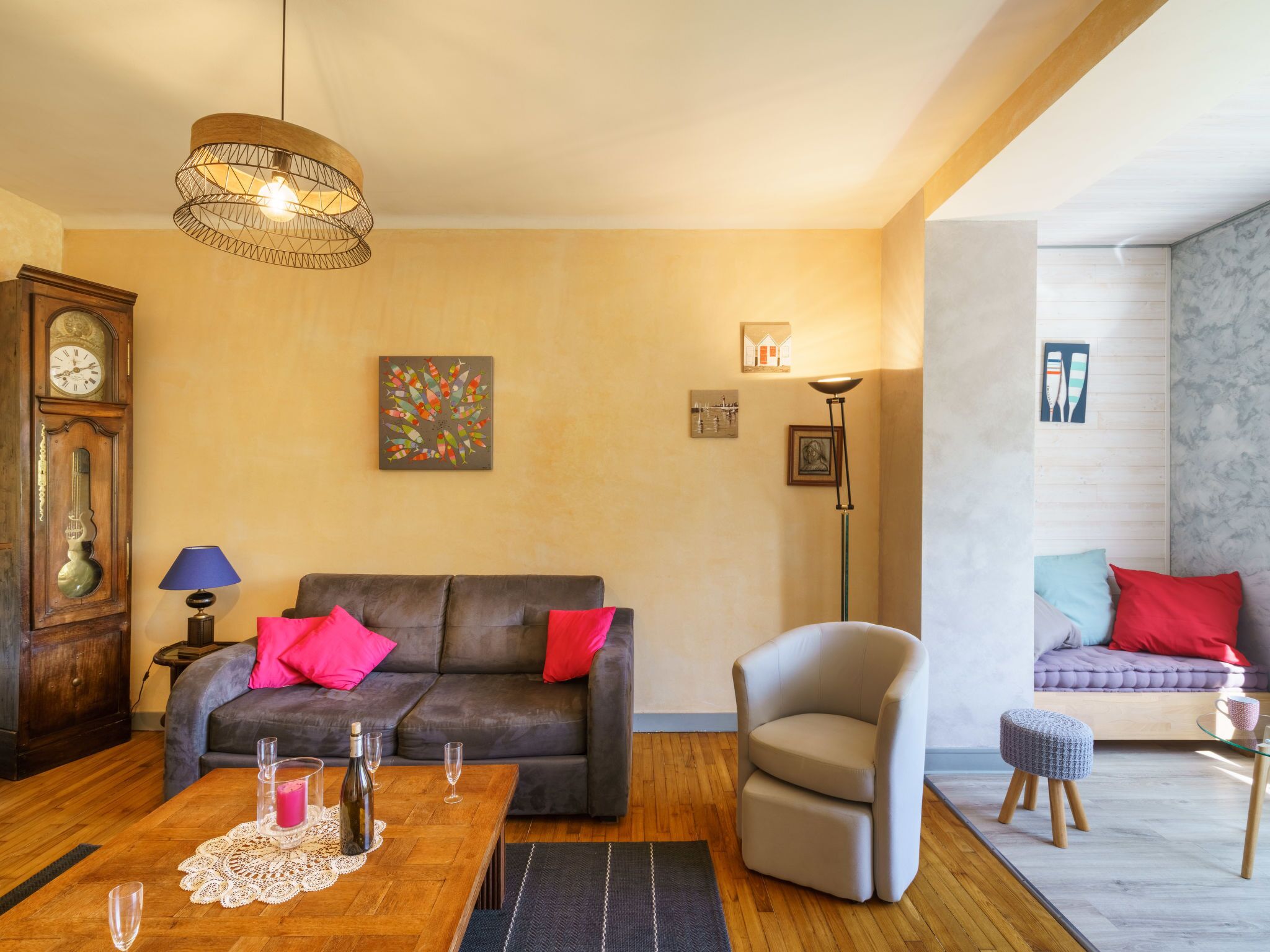 Ein gemütliches Wohnzimmer mit einem dunkelbraunen Ledersofa, einem Couchtisch mit Getränken, einem modernen Sessel und einem kleinen Hocker.