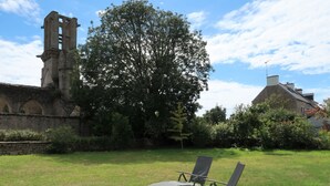 A grassy area with two lounge chairs and a stone structure in the background.