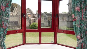 A corner room with a bay window overlooking an ancient stone structure.