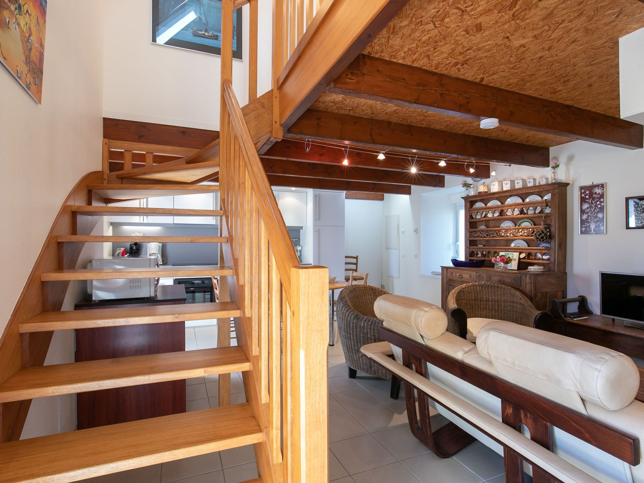 A wooden staircase leading to a living area with a sofa and a dining table.