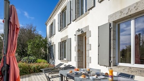 A patio with a table set for dining, outdoor chairs, and a covered umbrella. - Balade Océane by Interhome (Tregunc)
