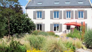 A two-story house with a white facade, grey shutters, and a red umbrella in the front garden. - Balade Océane by Interhome (Tregunc)