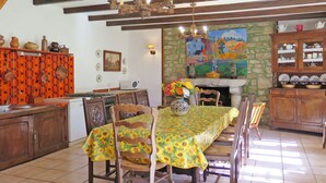 Comedor con una mesa dispuesta para seis personas, rodeada de sillas de madera. Un jarrón con flores está sobre la mesa.