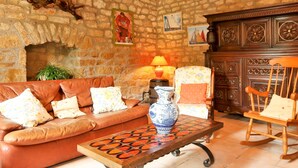Un salón acogedor con pared de piedra, chimenea, sofá de cuero y mesa de centro de madera.