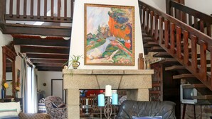 A living room with a stone fireplace, a leather sofa, a chair, and a staircase.