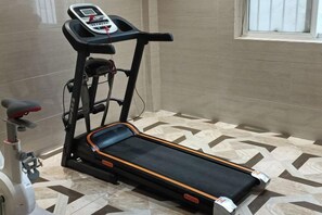 A treadmill with a digital display, a stationary bike, and a patterned floor. - Shengtong Hotel (Lijiang)