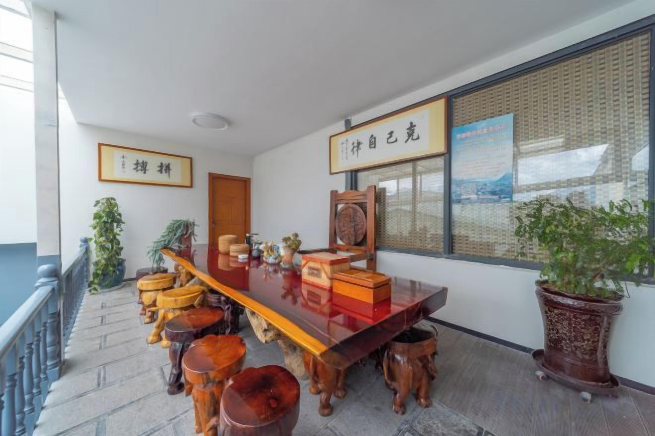 Habitación de estilo tradicional con una larga mesa de madera, varios taburetes y una planta en maceta.