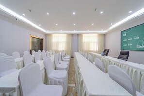 A conference room with a long table, chairs, a projector screen, and a presentation area. - Shengtong Hotel (Lijiang)