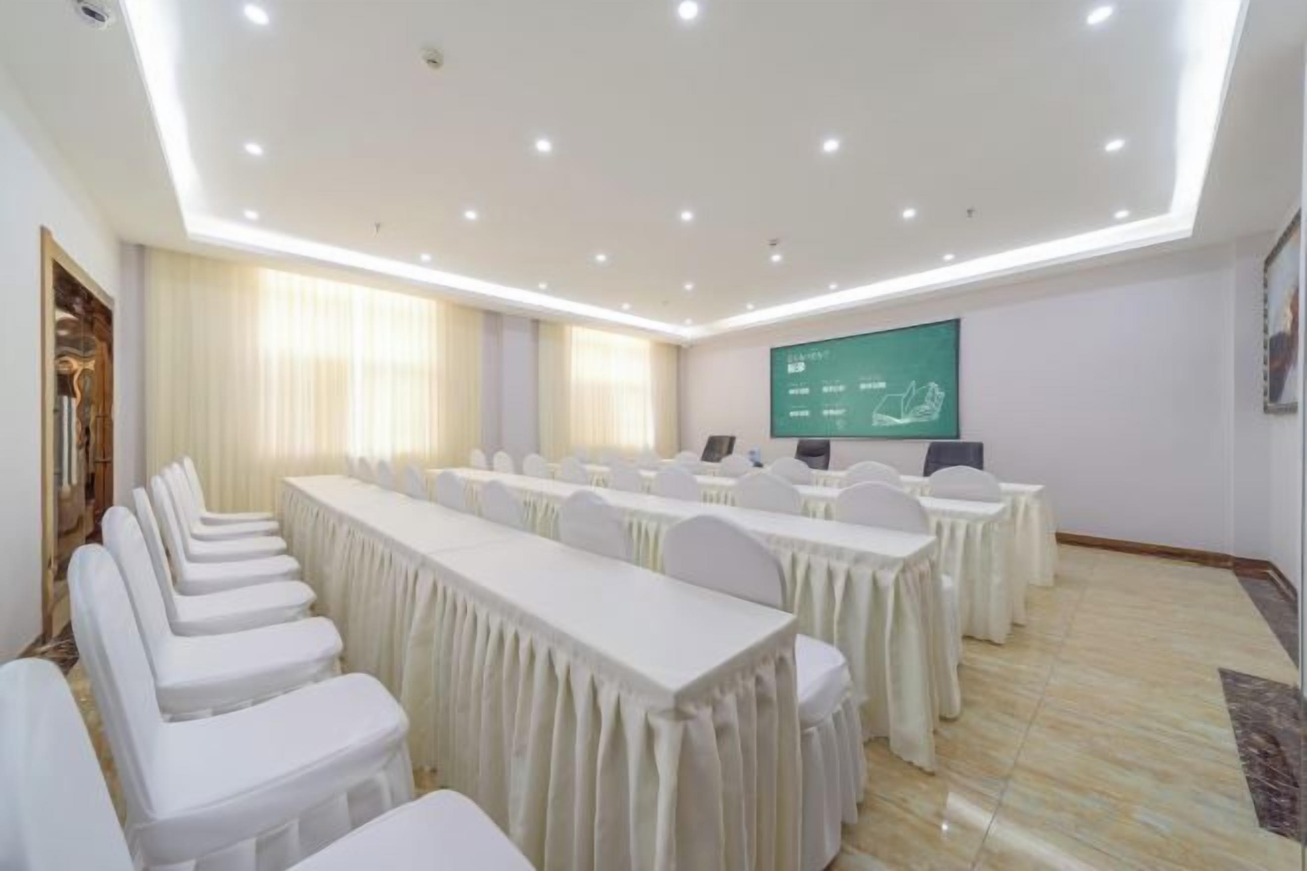 Un salón de conferencias con una larga mesa, sillas, una pantalla de proyector y una pizarra.
