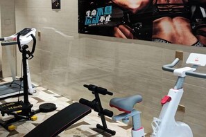A gym with exercise equipment including a treadmill, a stationary bike, and a bench. - Shengtong Hotel (Lijiang)