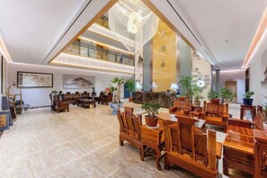 A spacious lobby with a high ceiling, wooden furniture, and a large open area with a view of the upper floor. - Shengtong Hotel (Lijiang)