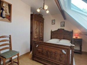 Une chambre à coucher avec un lit en bois, une chaise, une armoire et un tableau accroché au mur.