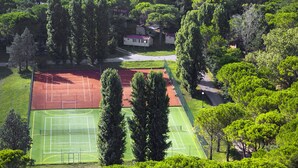 An aerial view of a tennis court surrounded by dense greenery and a small building. - Belvedere Pineta Camping Village by Interhome (Grado)
