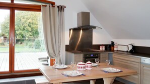Eine moderne Küche mit großem Fenster, einem eingebauten Backofen und einem Esstisch für vier Personen.